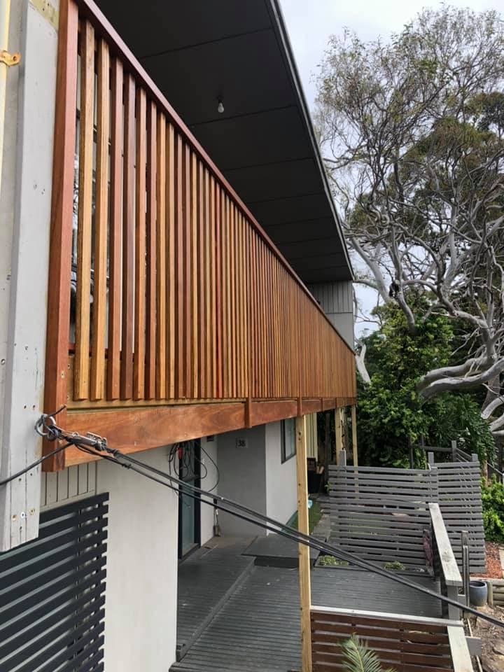 Hardwood vertical batten privacy screen on an elevated balcony, fixed to a hardwood frame with an even shadow gap between each batten