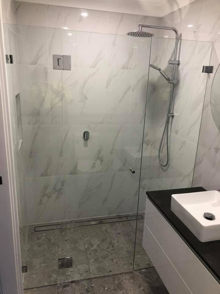 Renovated bathroom with a frameless glass shower screen, marble-look large format tiles, linear floor waste and a wall-hung vanity