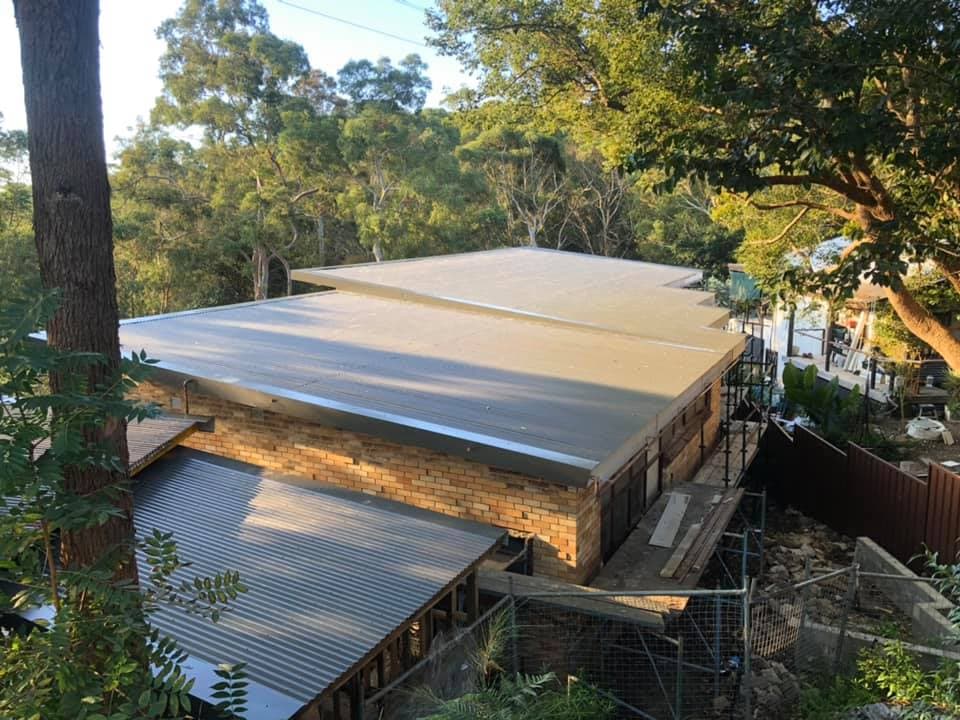 Completed extension with a new low-pitch metal roof over face brickwork, in a bushland setting